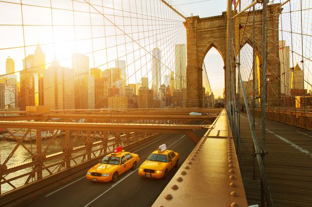 Two taxis driving across the Brooklyn Bridge